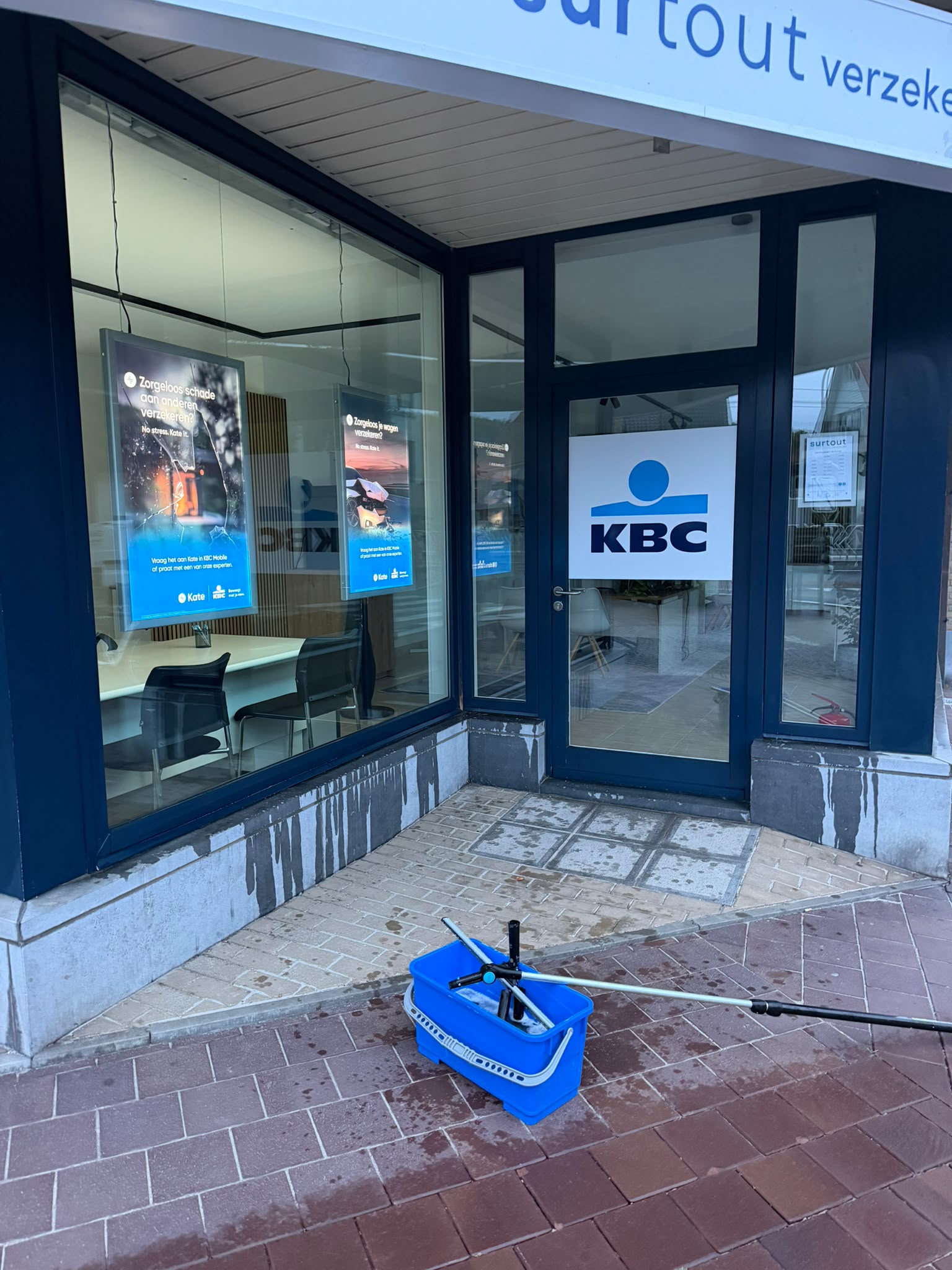 Kantoor van KBC verzekeringen met emmer en trekker klaar voor de ruiten