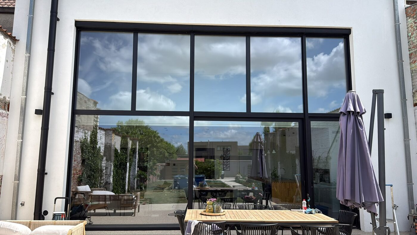 Grote glazen wand van een woning met wolken in de weerspiegeling
