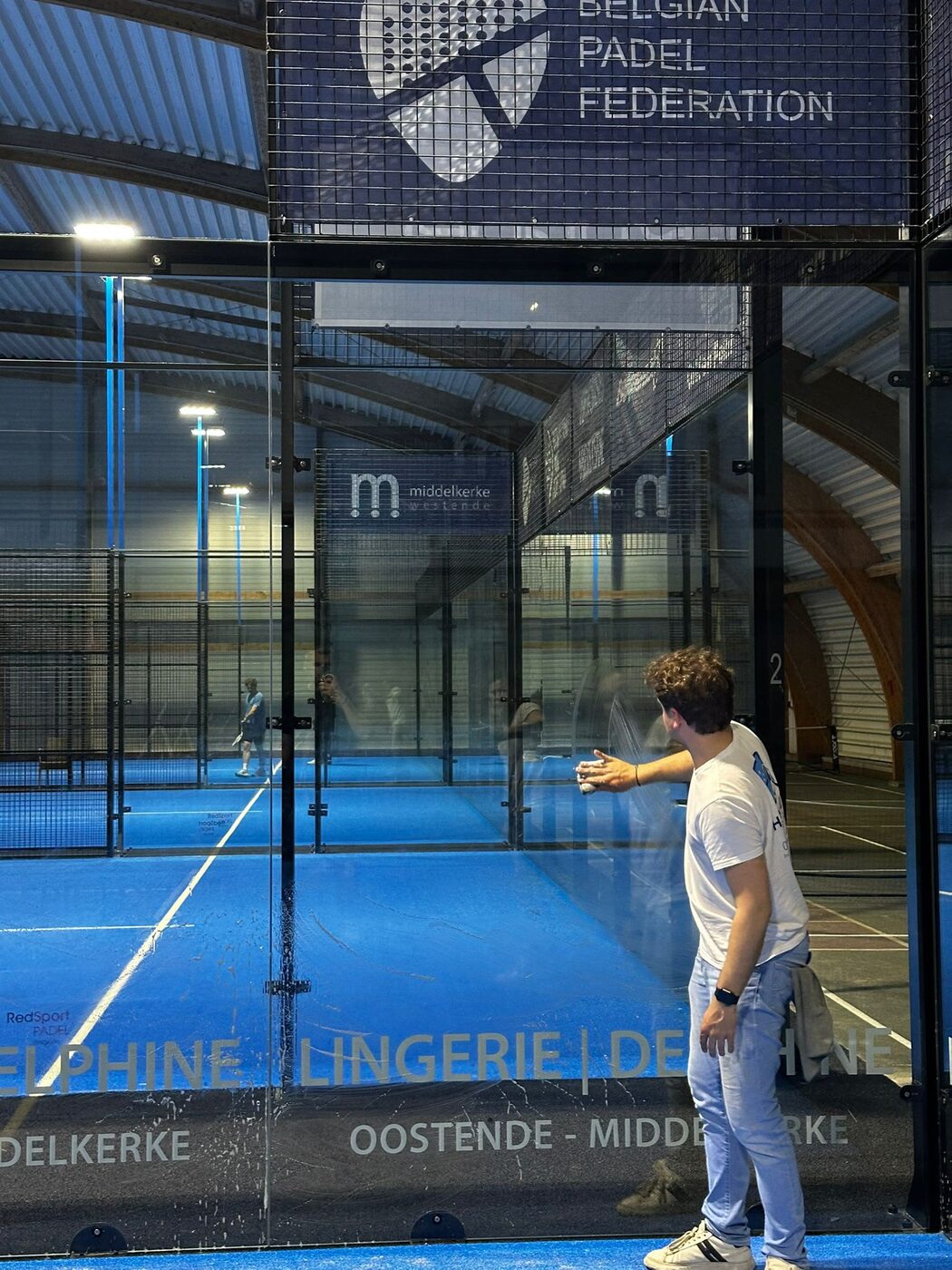 Tom reinigt de glazen wand van een padelhal in Middelkerke